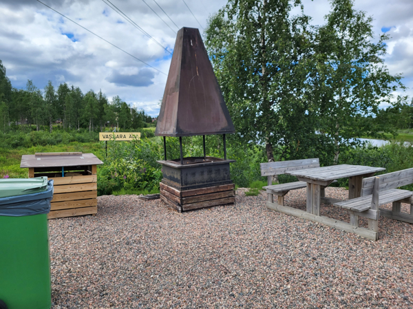 Vedförråd, eldstad med skorsten och bänkbord