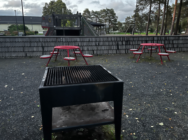 Grill med bänkbord i bakgrunden