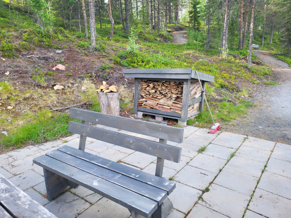 Sittbänk med vedförråd i bakgrunden