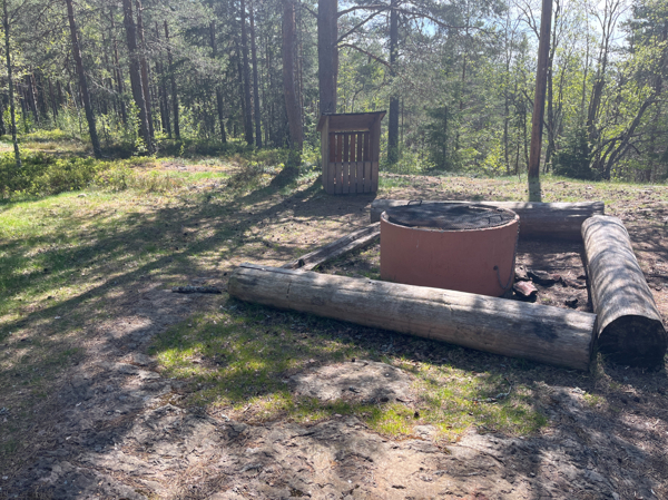 Eldstad med galler, stockar att sitta på och vedförråd