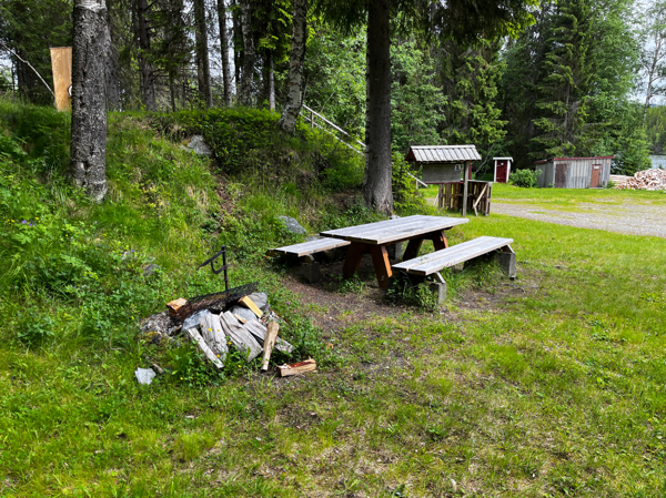 Eldstad och bänkbord med vedförrådet en bit bort