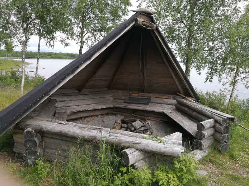 Timrat vindskydd med eldstad i mitten och tak som täcker hälften